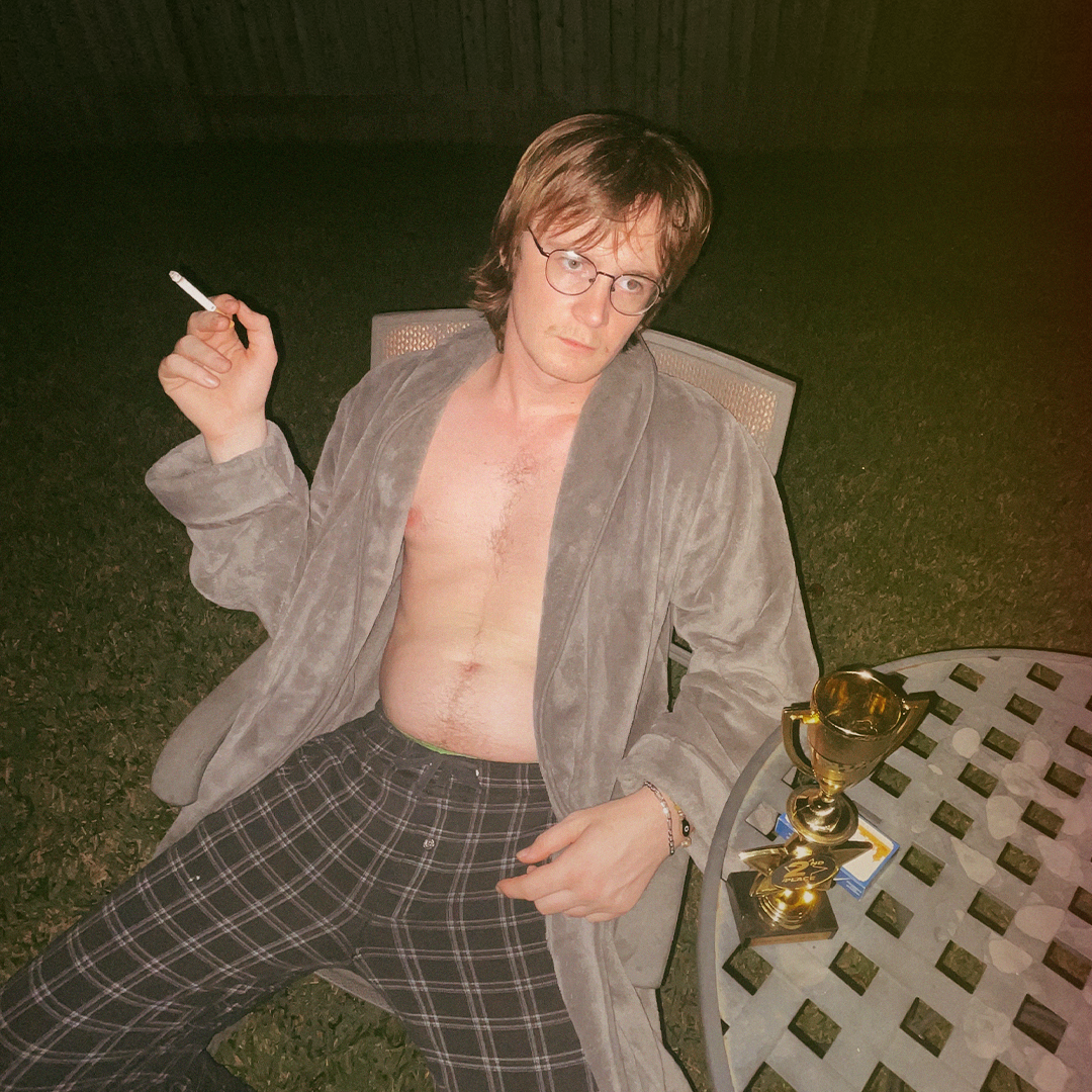 Quinn Decker smoking a cigarette with pink hair and a hat